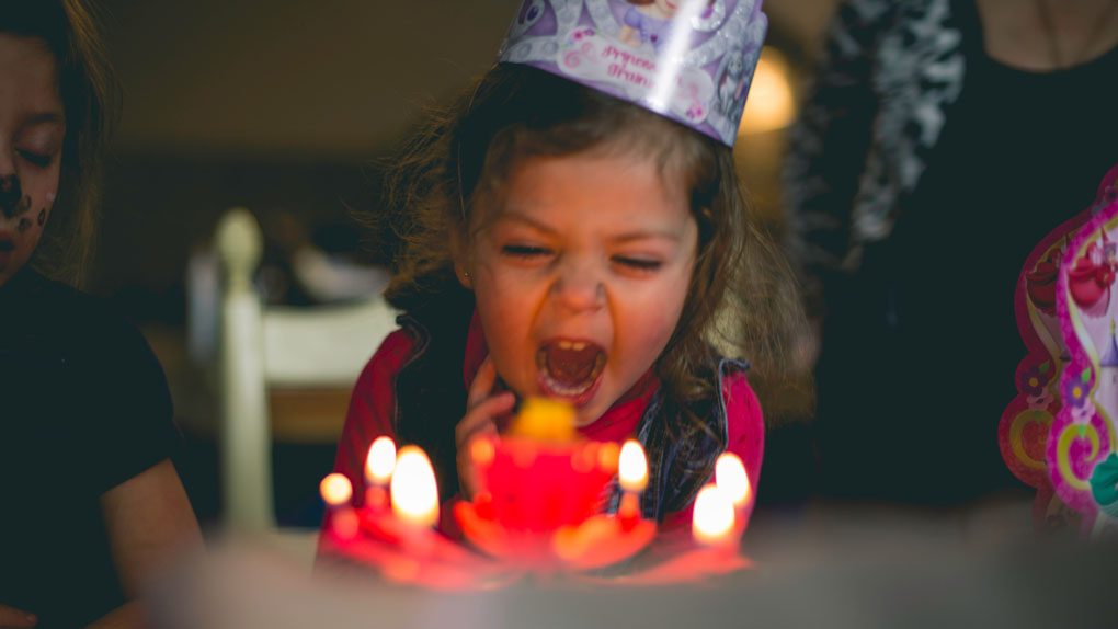 Geburtstagskind blässt Geburtstagskuchen an der Geburtstagsparty aus